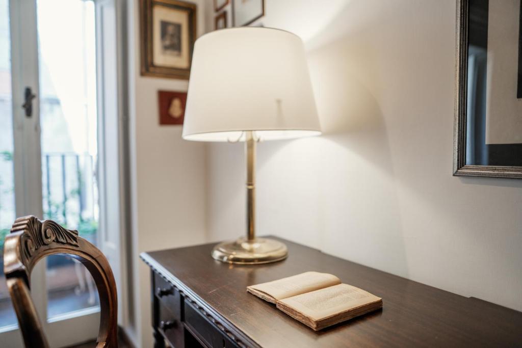 a lamp sitting on a desk with a book at Domus Quiritum Charming, Appartamento d'Epoca a Campo de' Fiori in Rome