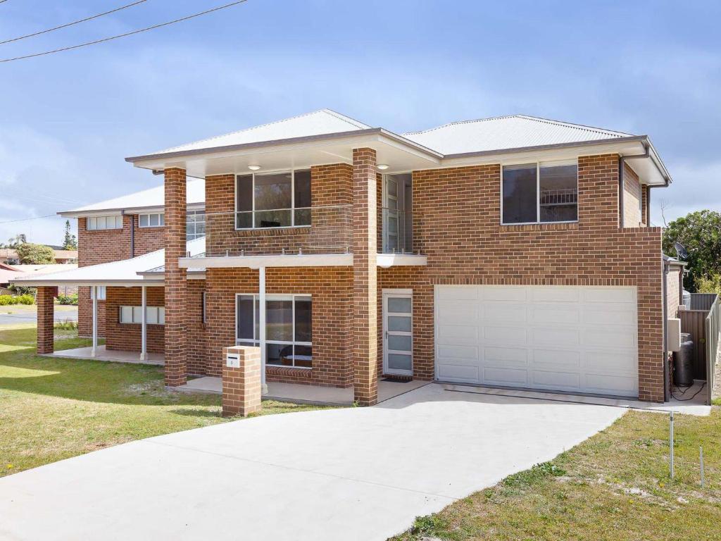 a brick house with a garage in front of it at 5b Bent Street large house with ducted air con foxtel and wifi in Fingal Bay