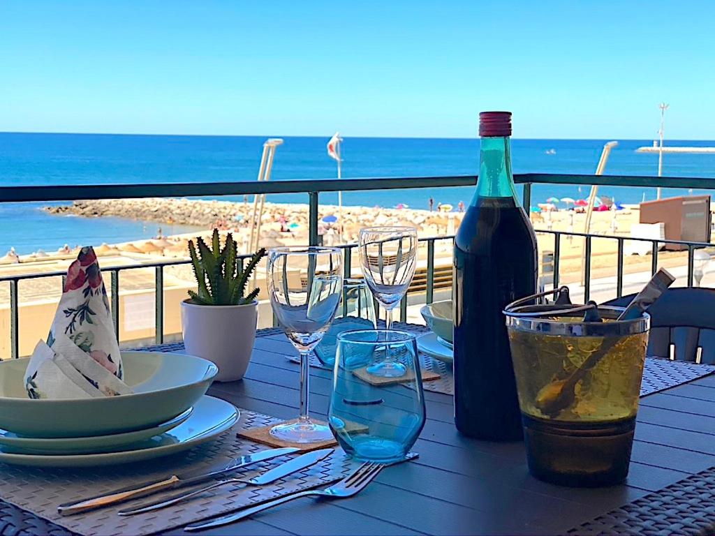 un tavolo con una bottiglia di vino e bicchieri in spiaggia di Lusitania T2 Frente Mar em Quarteira a Quarteira