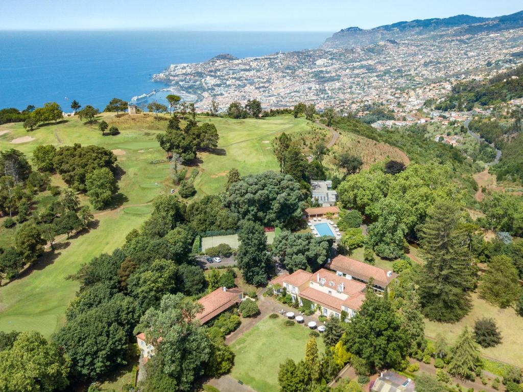 an aerial view of a house on a hill next to the ocean at Casa Velha do Palheiro Relais & Chateaux in Funchal