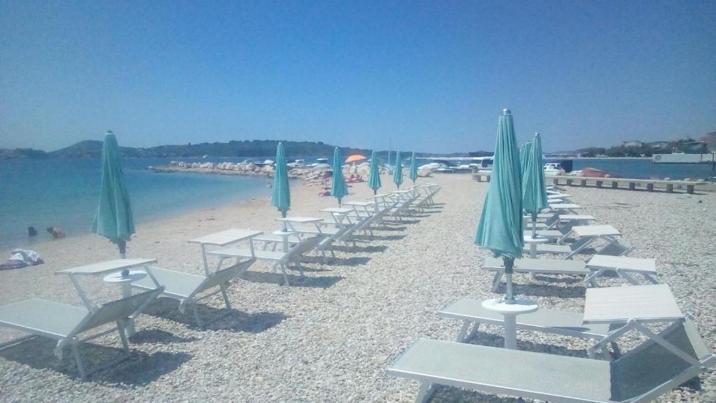 a row of chairs and umbrellas on a beach at STUDIO APARTMANI KIKI in Srima