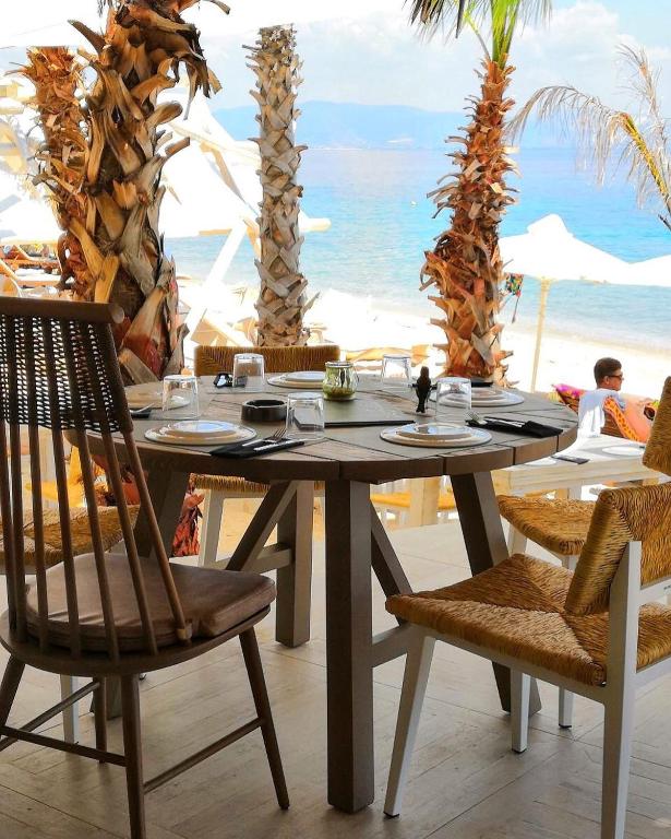 a wooden table with chairs and a table with a view of the ocean at Kohylia by La Scala Beach in Limenas