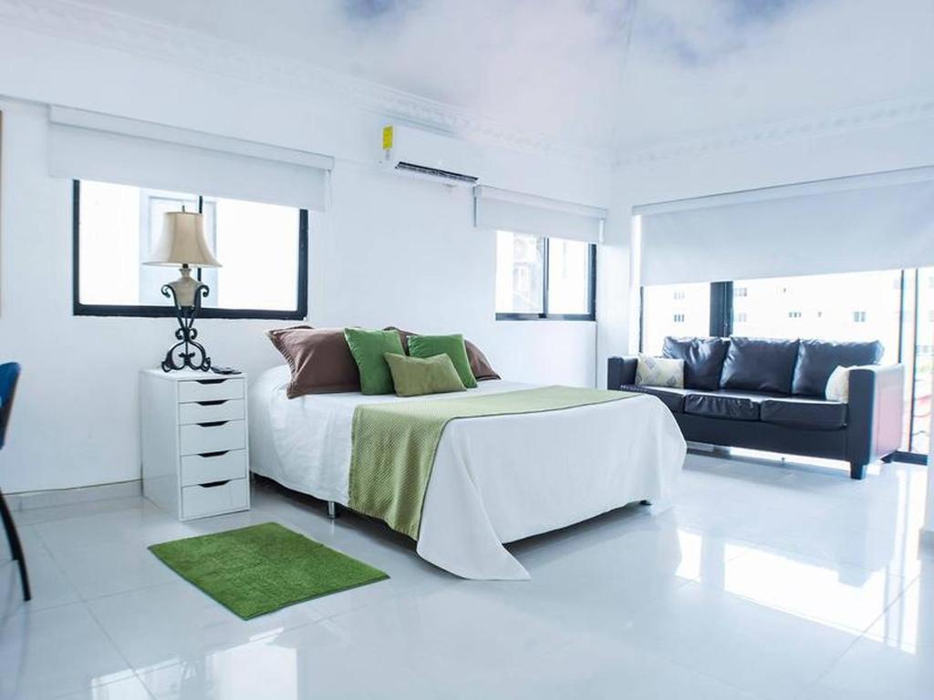 a white bedroom with a large bed and a couch at Malecon Cozy - Premium Plus 11 in Santo Domingo