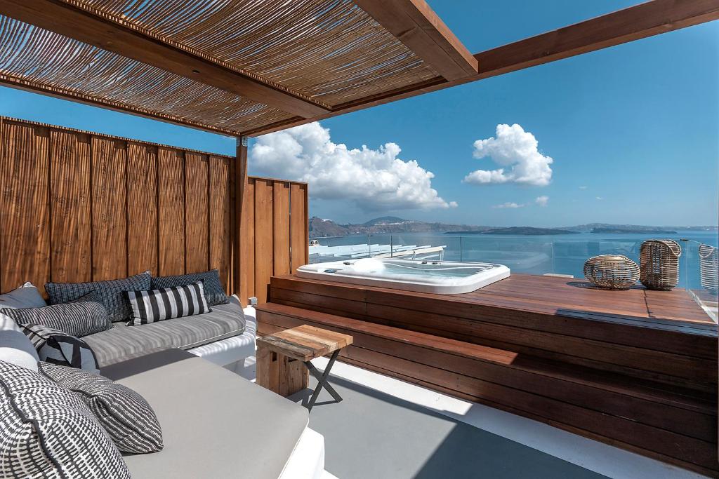 a balcony with a couch and a boat on the water at 3 Elements by Stylish Stays in Oia