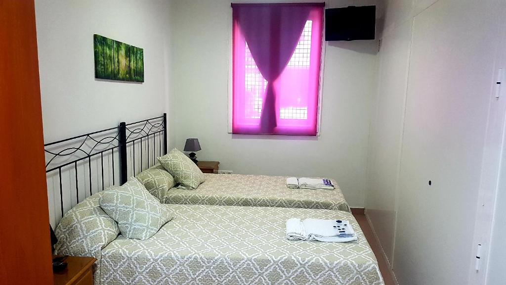 two beds in a room with a pink window at Apartamento Study 1 Select Real Caldas de Reis in Caldas de Reis