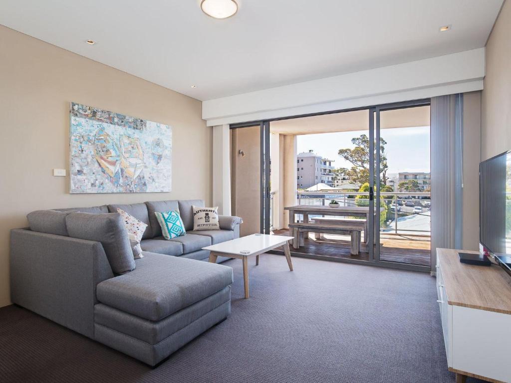 uma sala de estar com um sofá e uma televisão em Cote D'Azure, 13 61 Donald Street - Lovely unit air con, Wi-Fi, secure parking, complex lift and pool em Nelson Bay