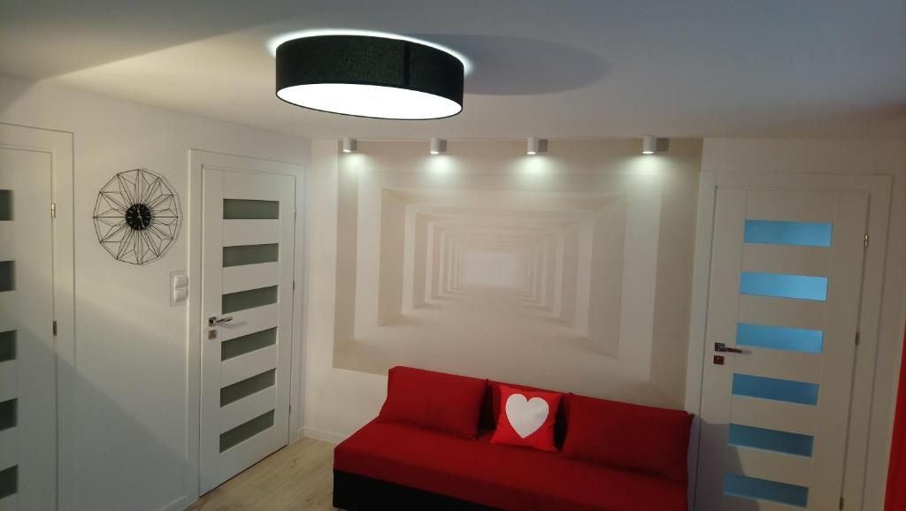 - un salon avec un canapé rouge et un oreiller pour le cœur dans l'établissement Apartament Jarzębinka, à Międzyzdroje