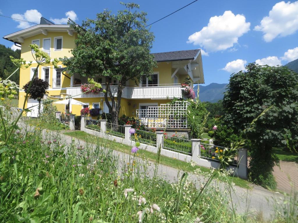 ein gelbes Haus mit einem Zaun und Blumen in der Unterkunft Ferienwohnung Kerschbaumer in Rangersdorf