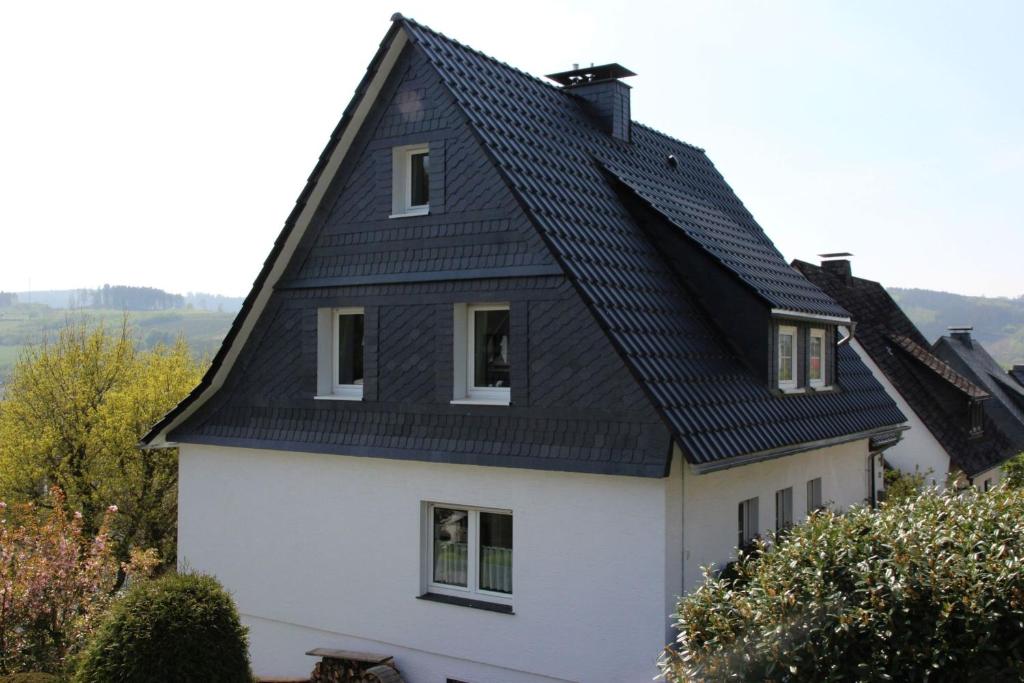 una casa bianca con tetto nero di Ferienwohnung Olsberg ad Assinghausen