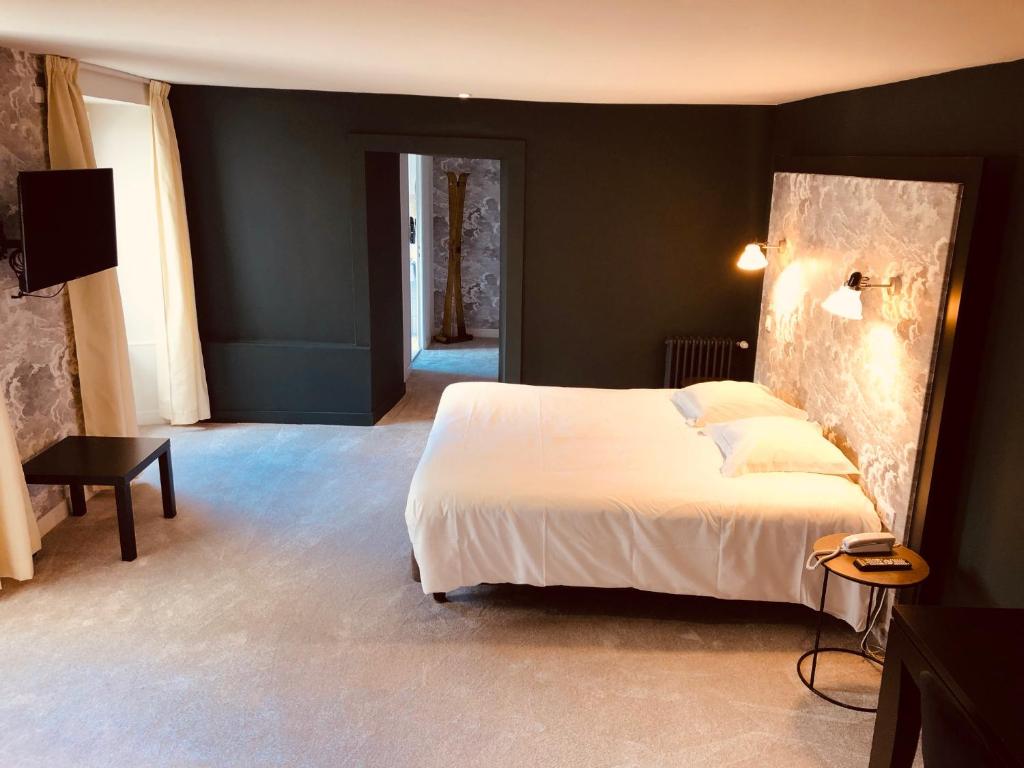 a bedroom with a large white bed with a mirror at Hôtel Le Cobh in Ploërmel