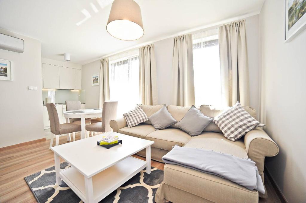 een woonkamer met een bank en een tafel bij Deluxe Modern Apartment Victoria Residence by Grand Apartments in Sopot