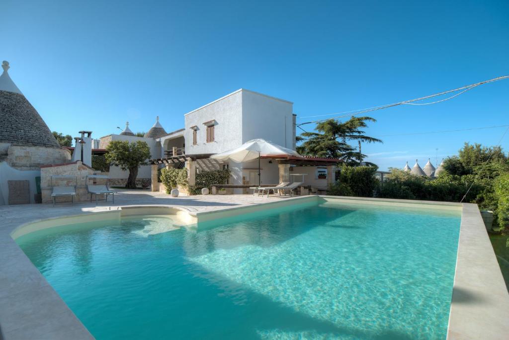 a swimming pool in front of a house at Trulli La Piazzetta by Rentbeat in Cocolicchio