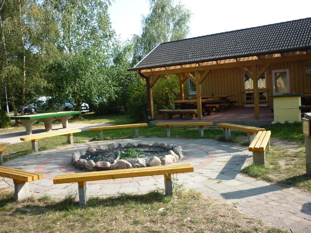 eine Gruppe von Bänken in einem Park mit einer Feuerstelle in der Unterkunft Gruppenbungalow-Waldhaus-Am Ferienpark in Mirow