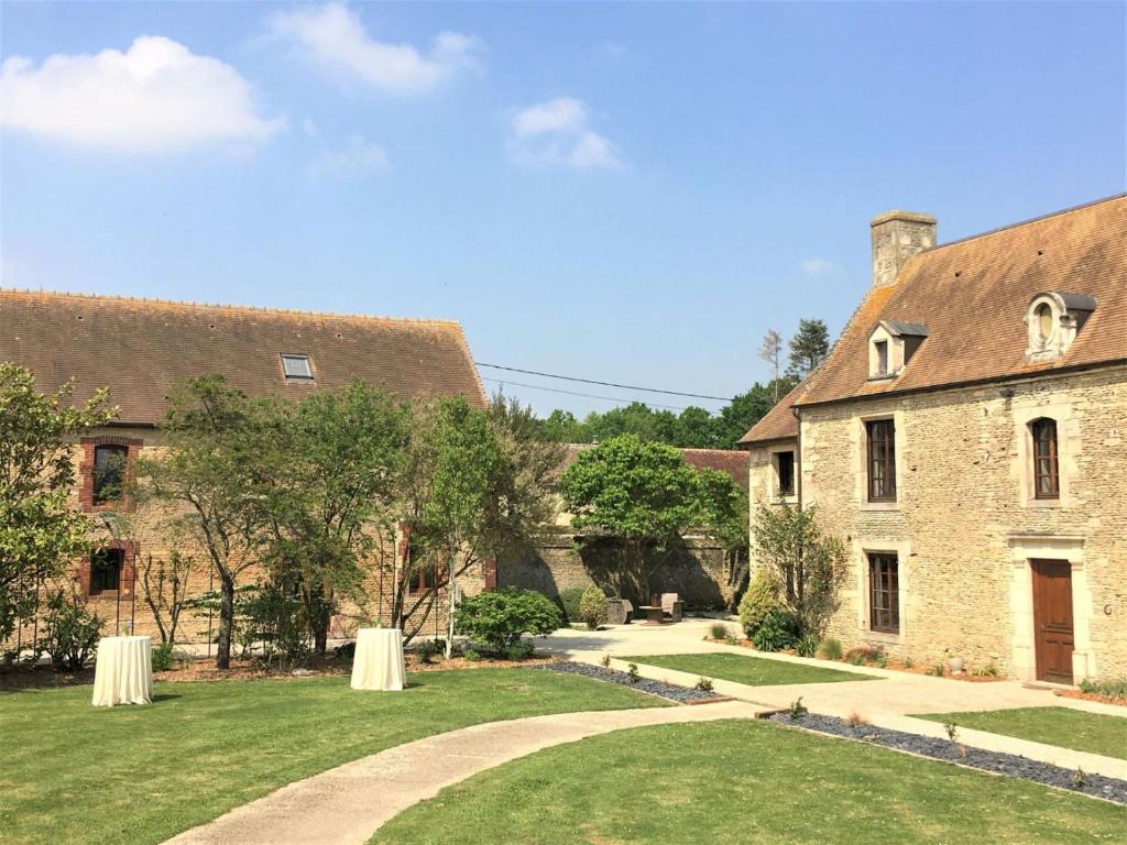 - un grand bâtiment en pierre avec une pelouse dans l'établissement Domaine du Bû sur Rouvres, à Le Bû-sur-Rouvres