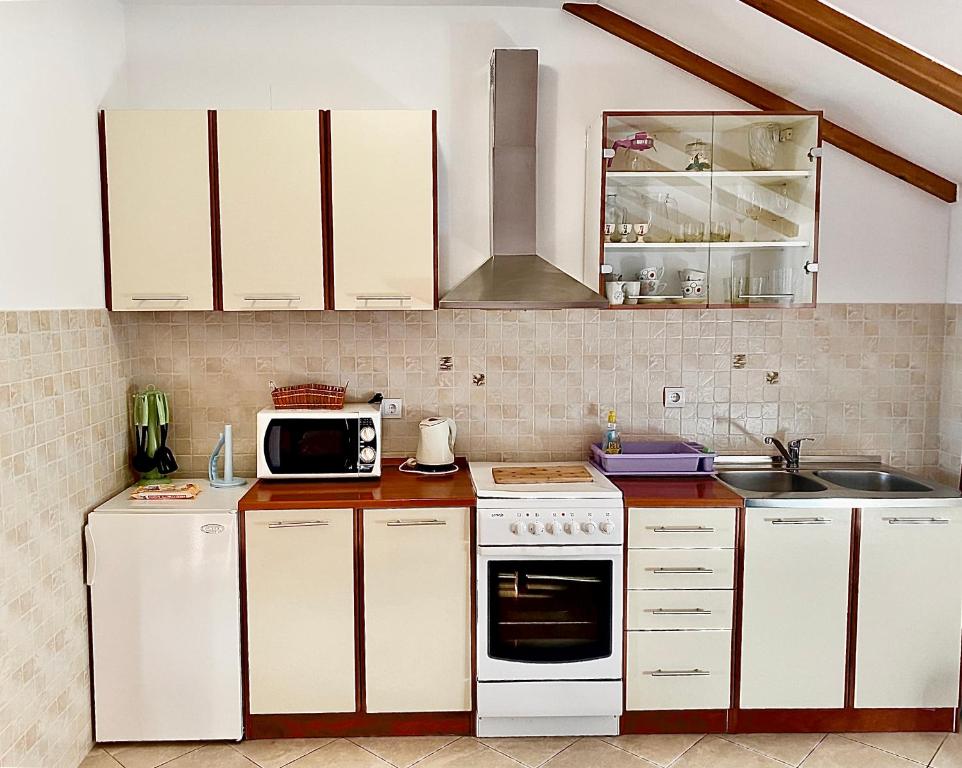 a kitchen with white cabinets and a microwave at Apartments Miljas in Cavtat