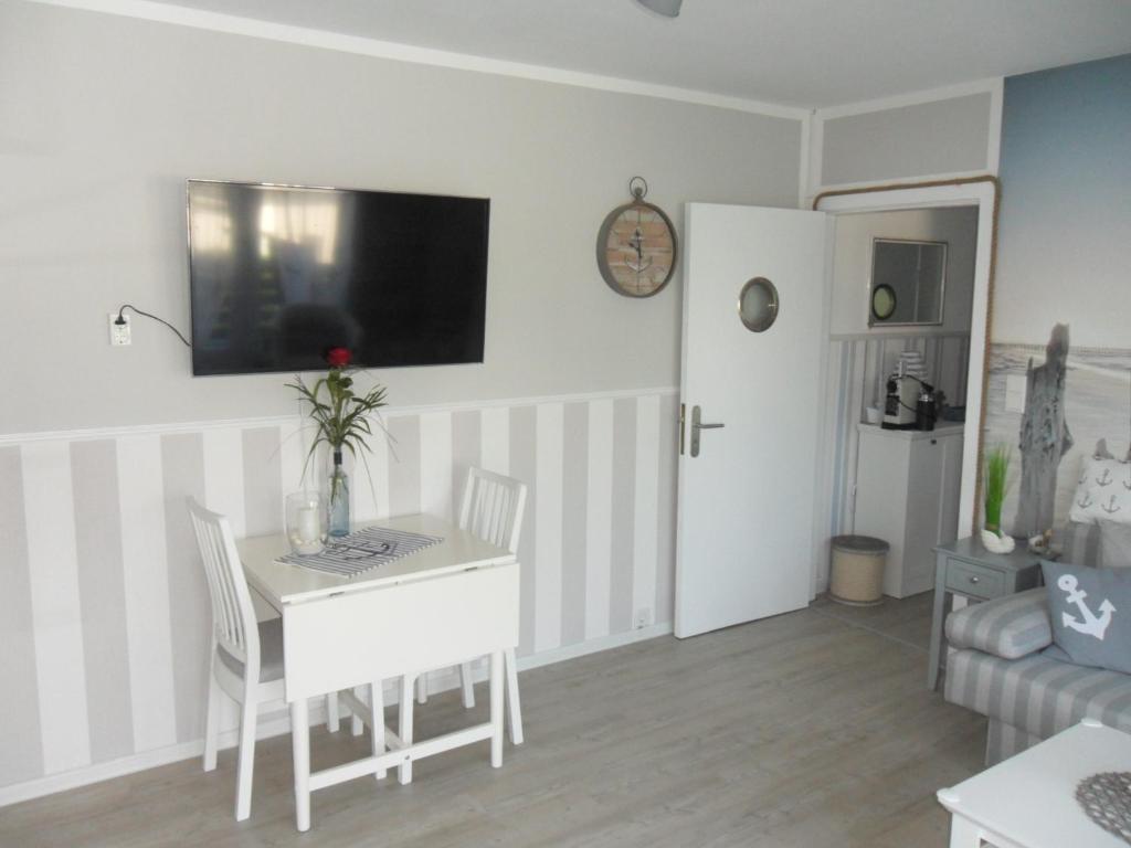 a living room with a table and a tv on the wall at Seemannskiste in Grömitz
