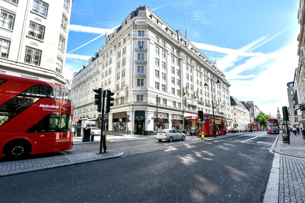 a red double decker bus driving down a city street at Strand Palace in London