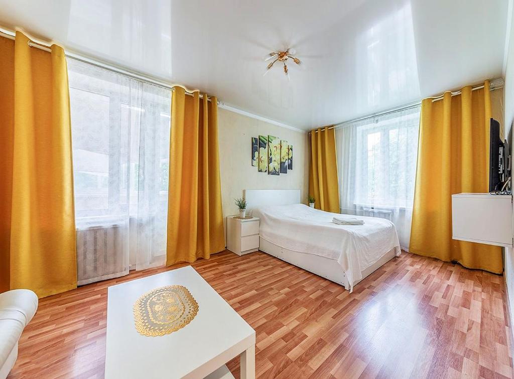 モスクワにあるApartment Hanaka Shchelkovskoe 49のベッドルーム1室(黄色いカーテン、ベッド1台、テーブル付)