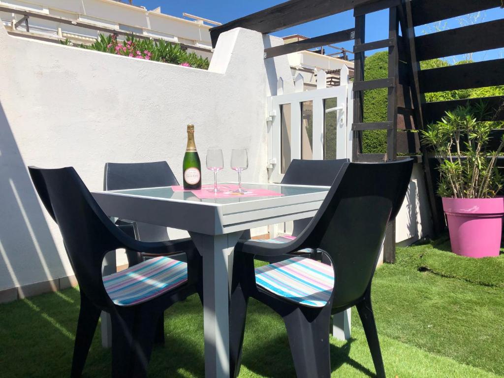 una mesa con 2 sillas y una botella de vino en Centre Naturiste Villas studio, en Cap d'Agde