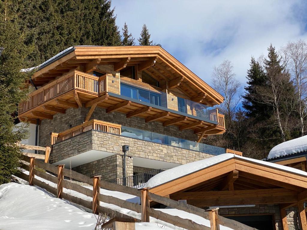 a log home with a wrap around deck in the snow at Lavender Hill - Summer holiday & ski chalet/villa in Saalbach-Hinterglemm