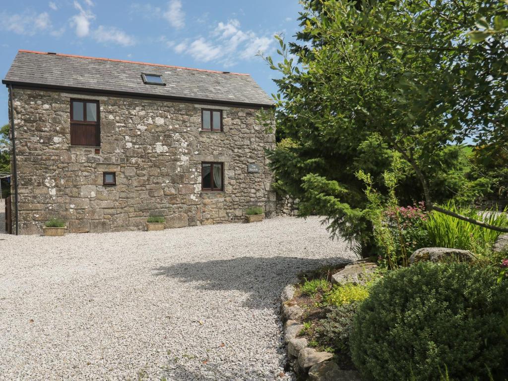 an old stone house with a gravel driveway at The Hayloft in Liskeard