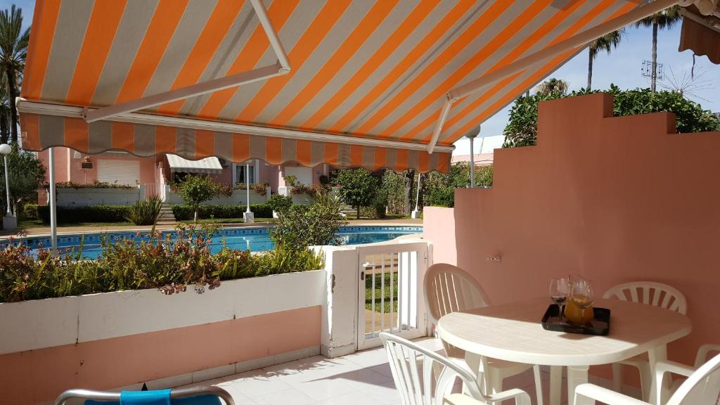 a table and chairs under an umbrella next to a pool at Jazmines 5 in Denia