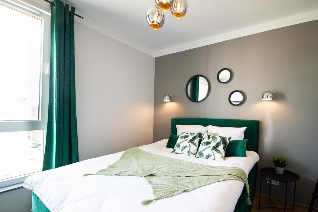 een slaapkamer met een bed met groene gordijnen en een raam bij Patio Praga Metro Apartment in Warschau