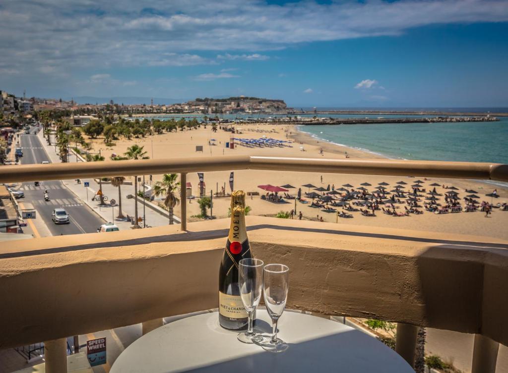 a bottle of champagne and two glasses on a table with a beach at Theo Beach Hotel Apartments in Rethymno Town