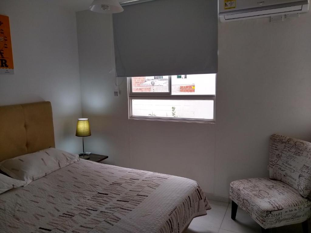 1 dormitorio con cama, ventana y silla en CH3 Moderno apartamento amoblado en condominio RNT-1O8238 en Valledupar