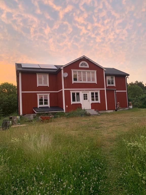 a red house with a field in front of it at Charming house on large property on Vato in Vätö