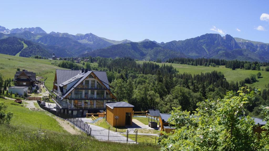 a house on a hill with mountains in the background at Apartamenty Bachledzki Wierch in Zakopane