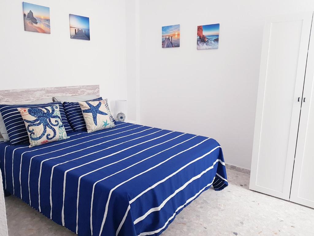 um quarto com uma cama listrada em azul e branco em Conil Centro & Playa, descanso perfecto, Aire Ac y WIFI -SOLO FAMILIAS Y PAREJAS- em Conil de la Frontera