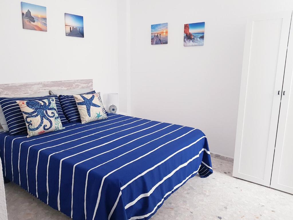 a bedroom with a blue and white striped bed at Conil Centro & Playa, descanso perfecto, Aire Ac y WIFI -SOLO FAMILIAS Y PAREJAS- in Conil de la Frontera