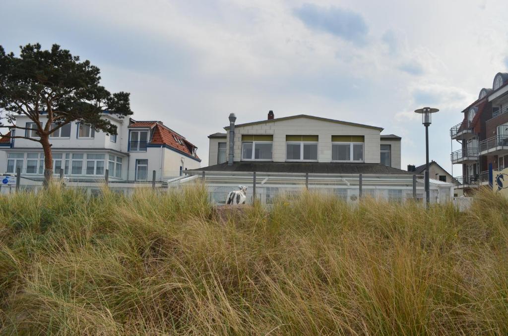 ein Haus, das auf einem Feld mit hoher Wiese liegt in der Unterkunft Schipperhus in Timmendorfer Strand