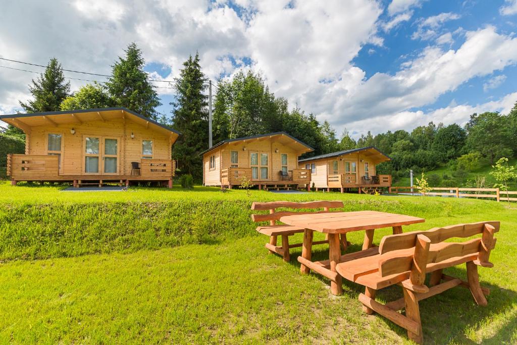 a picnic table and benches in a field with houses at Domki z Papieru in Polańczyk