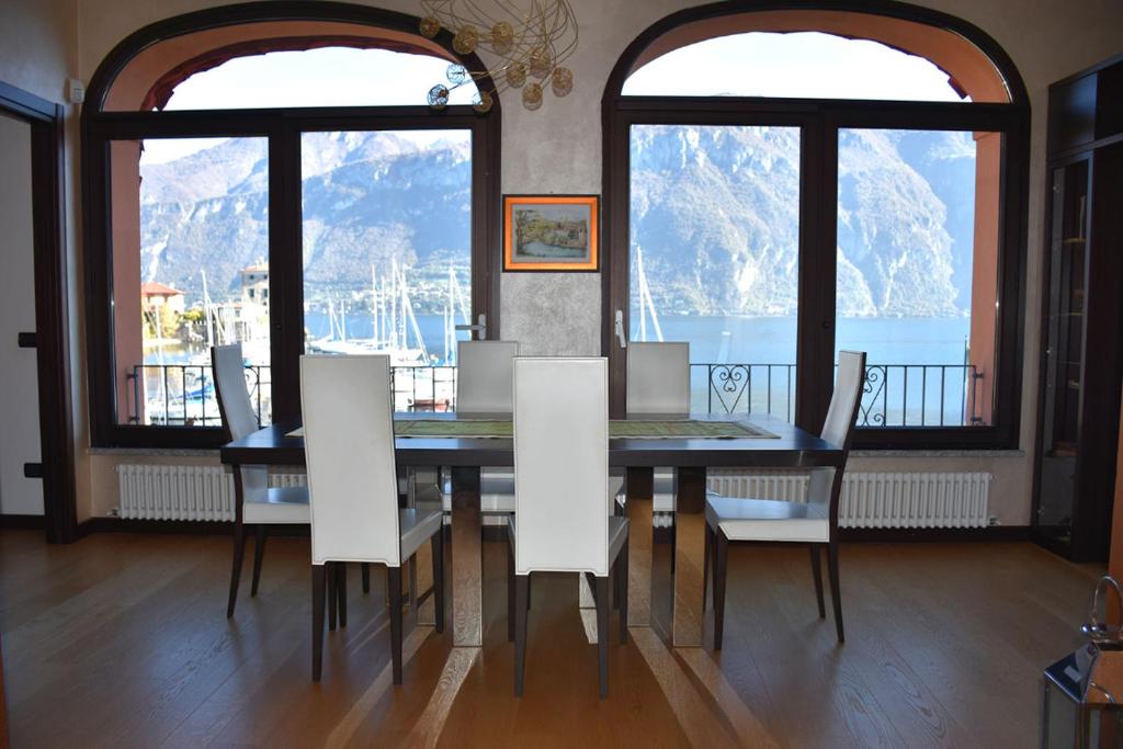 a dining room table with white chairs and windows at BELLAGIO LAKESIDE APARTMENT in Bellagio