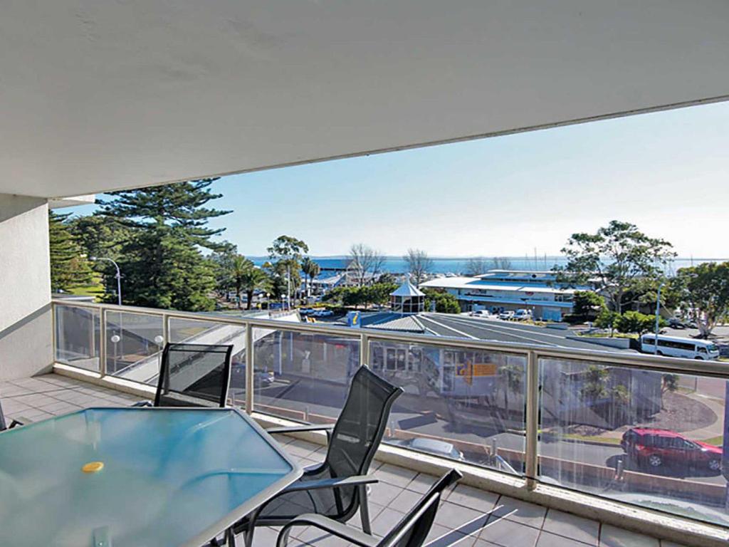 a balcony with a table and chairs and a view of a parking lot at Nelson Towers, 9,71a Victoria Parade - unit in the heart of Nelson Bay with water views, air conditioning and Wi-Fi in Nelson Bay