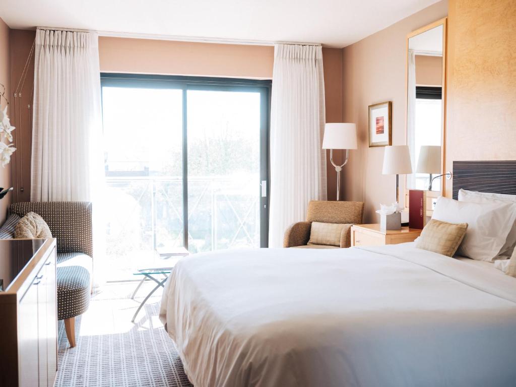 a hotel room with a bed and a large window at The Club Hotel & Spa Jersey in Saint Helier Jersey