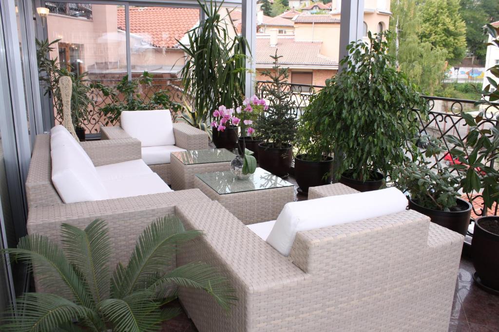 ヴェリコ・タルノヴォにある ホテル コンコルドの白い家具と鉢植えの植物が備わるバルコニー