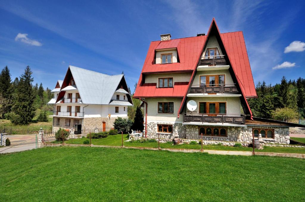 una casa grande con techo rojo en un campo verde en Pokoje Gościnne U Marysi, en Zakopane