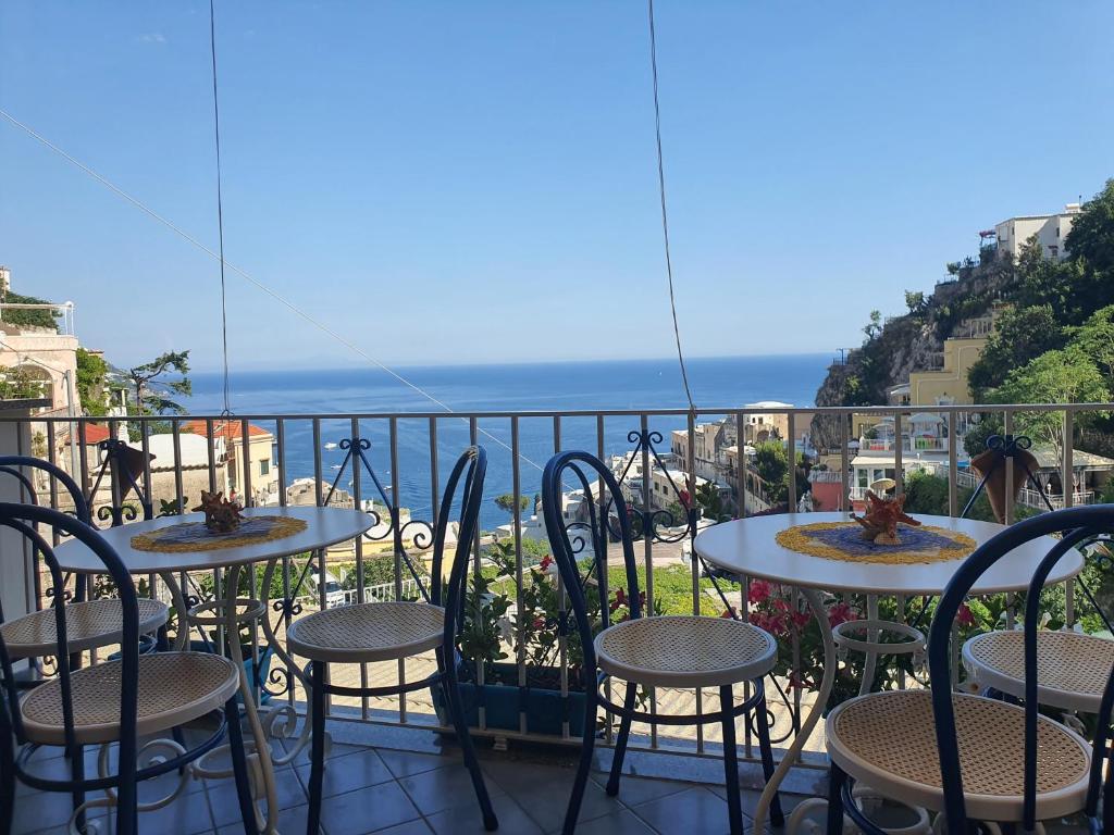 balcone con tavoli, sedie e vista sull'oceano di Villa Celentano a Positano