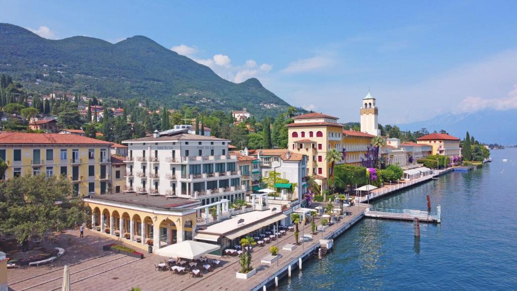 vista para uma cidade sobre a água com edifícios em Hotel Du Lac em Gardone Riviera