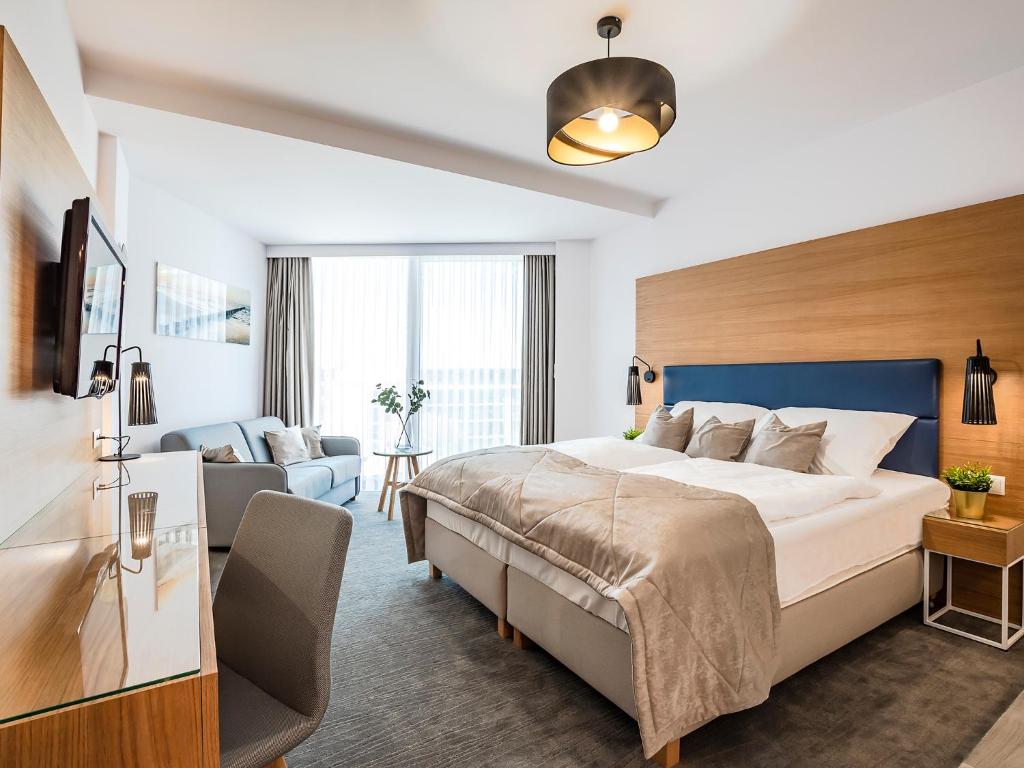 Cette chambre comprend un grand lit et un canapé. dans l'établissement VacationClub – Seaside Park Apartament 644, à Kołobrzeg