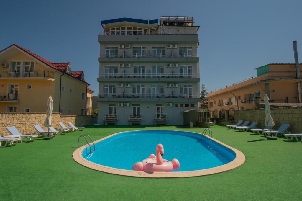 a person laying in a pool in front of a building at Hotel Olguta in Eforie Nord