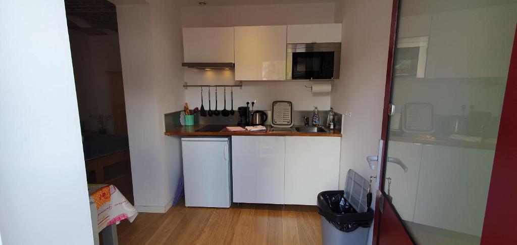 a small kitchen with white cabinets and a wooden floor at Au Petivall Studio in Achicourt