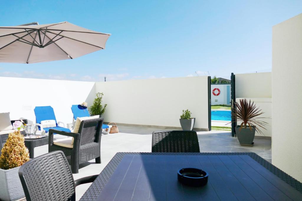 a patio with a table and chairs and an umbrella at Baleal poolfront apartment in Baleal