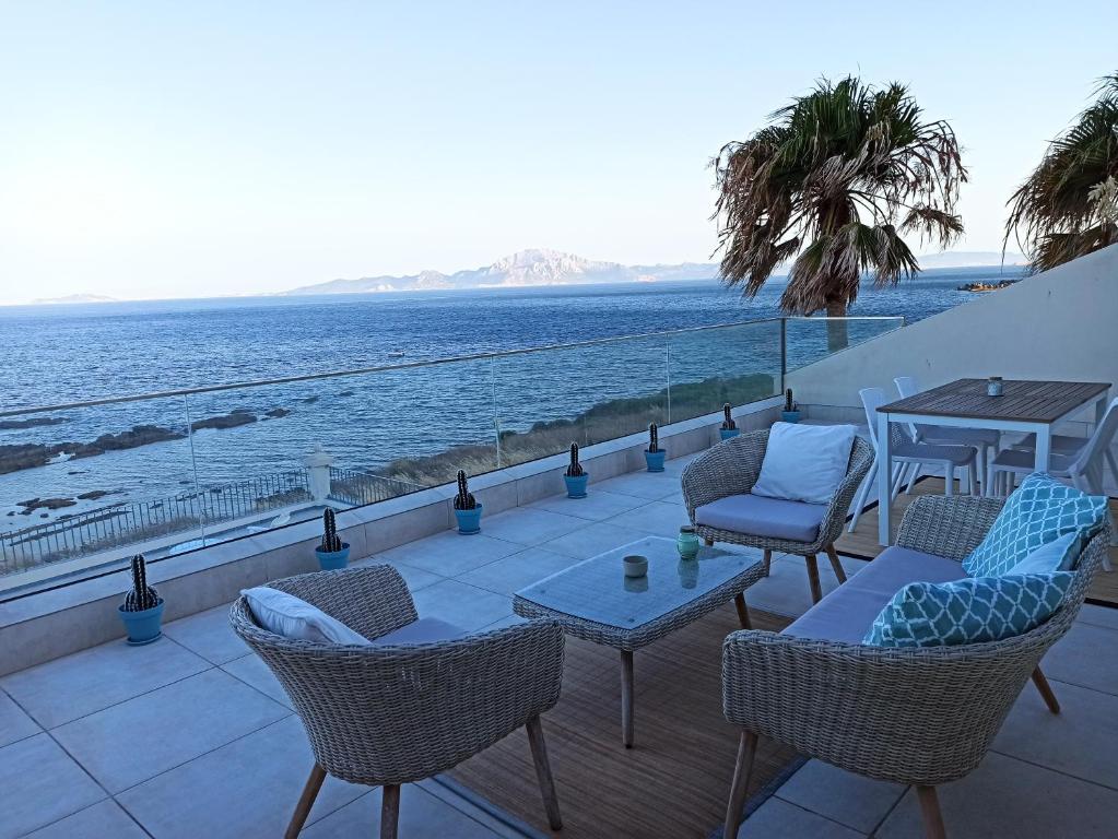 eine Terrasse mit Stühlen und Tischen und Meerblick in der Unterkunft Punta Carnero Hostal in Algeciras
