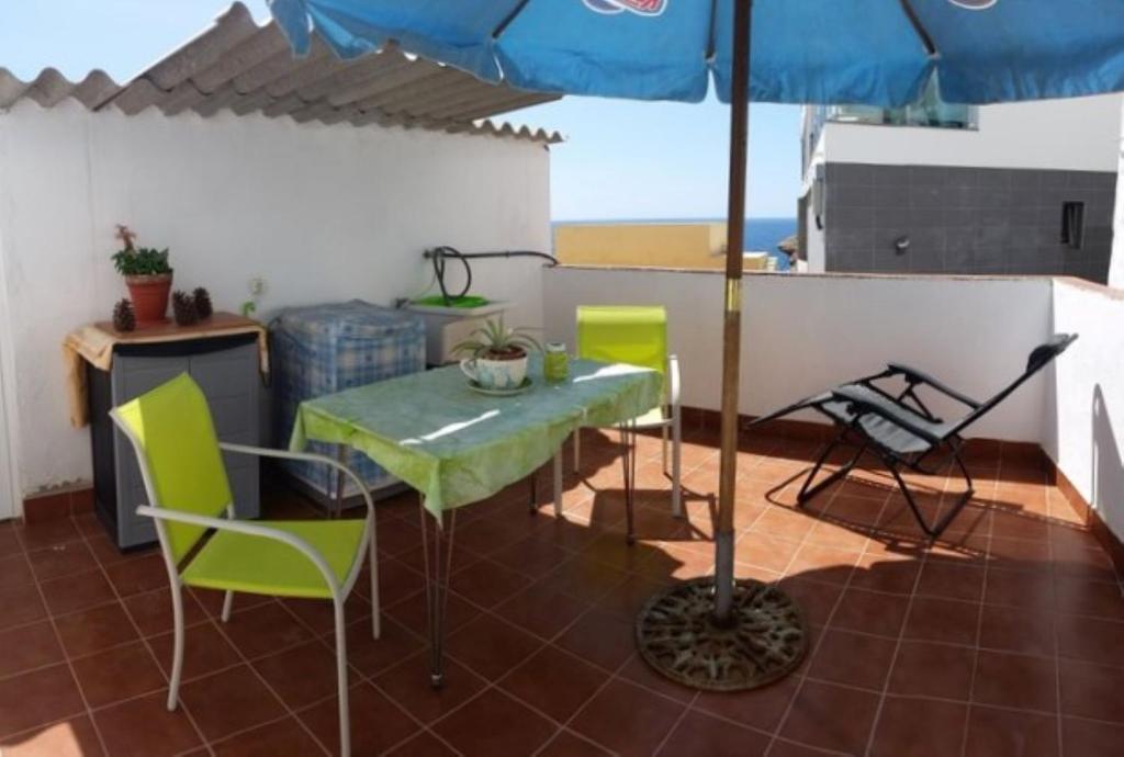 a patio with a table and chairs and an umbrella at Charming Oceanfront House in Puerto de Mogn, Gran Canaria in Puerto de Mogán