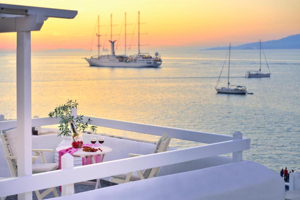 a balcony with a table and boats in the water at Marietta's in Mikonos