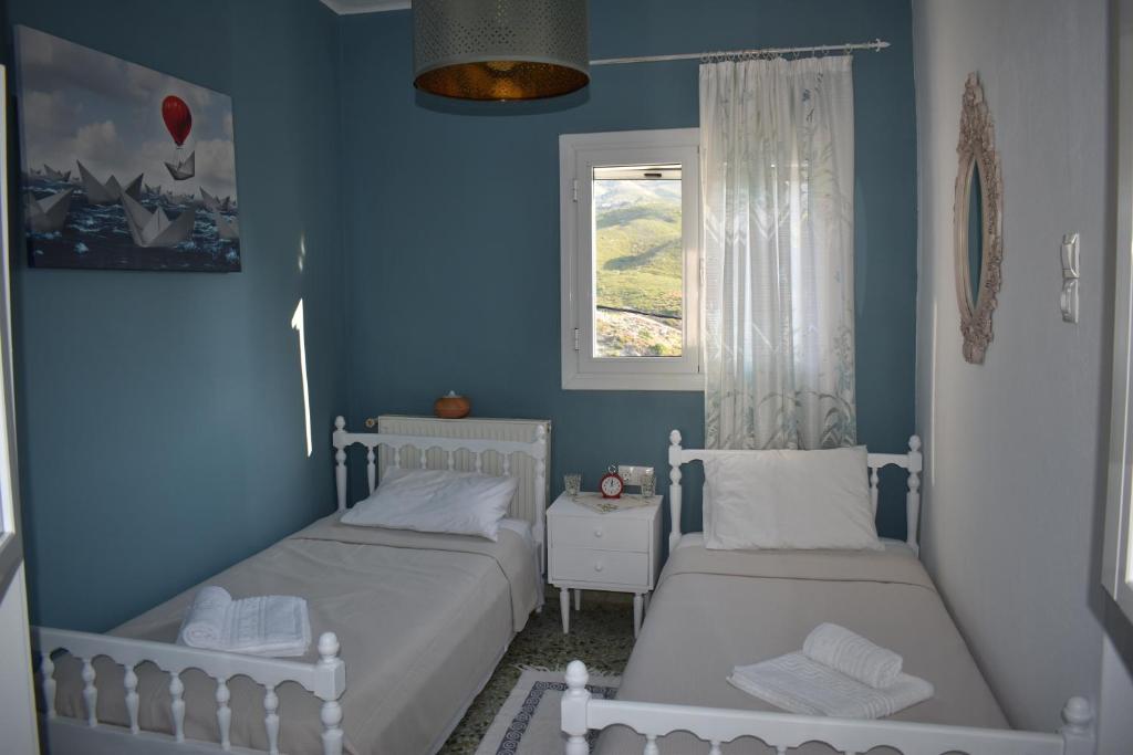 1 dormitorio azul con 2 camas y ventana en Dolihis gi, Poseidon, en Gialiskari
